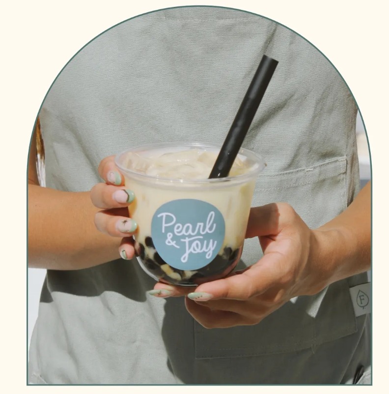 Hand holding fresh boba milk tea with tapioca pearls